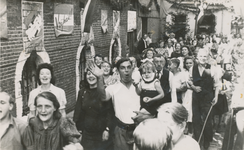 860694 Afbeelding van feestende mensen in een bevrijdingsoptocht door de Achterstraat in Wijk C te Utrecht.